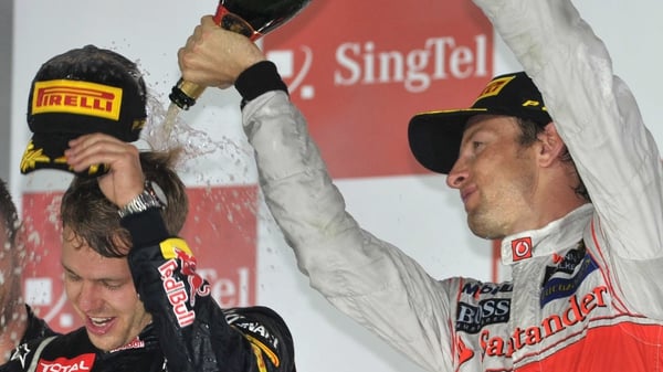 Jenson Button (R) pours champagne over Sebastian Vettel in Singapore