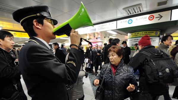 A station attendant uses a loudspeaker to explain the train service situations in Tokyo following the earthquake