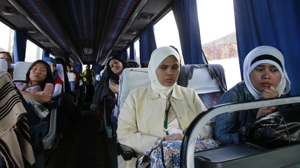 Asian women who were working in Syria are seen inside a bus leaving the war-torn country with the help of the International Organisation for Migration