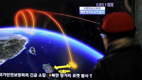 Travellers watch a TV screen broadcasting news of the launch in Seoul