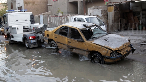 An Iraqi traffic police truck tows away a taxi cab after it was damaged in an explosion in the Karada district of Baghdad