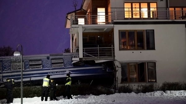 Policemen stand in front of a local train that derailed into a residential building in Saltsjoebaden, Sweden