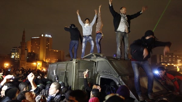 Protesters stand on a police vehicle in Cairo's Tahrir Square