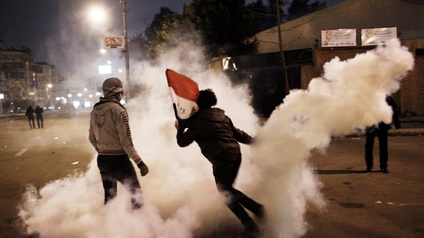 A protester throws a tear gas canister back towards police in Cairo
