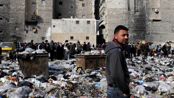 People pictured in a bazaar next to a rubbish heap in the northern city of Aleppo