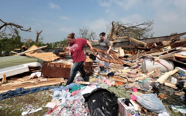 Two neighbours help clean debris from a mobile home after it was destroyed by the tornado