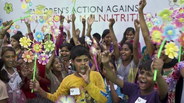 Indian children hold pinwheels, with each petal representing a child death caused by malnutrition, during a Global Day of Action against Global Hunger