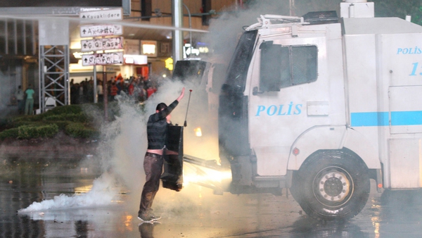 Protesters take cover from water cannon during clashes with police at a demonstration in Ankara