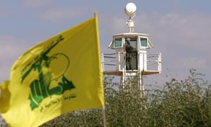 A Hezbollah flag flies as a member of the UN Interim Force in Lebanon stands in a lookout tower