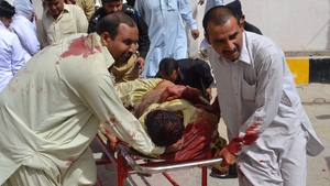 Pakistani policemen carry an injured colleague into a hospital in Quetta