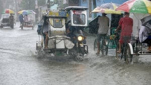 Residents commute along a flooded stretch of road during heavy rain in the suburbs of Manila
