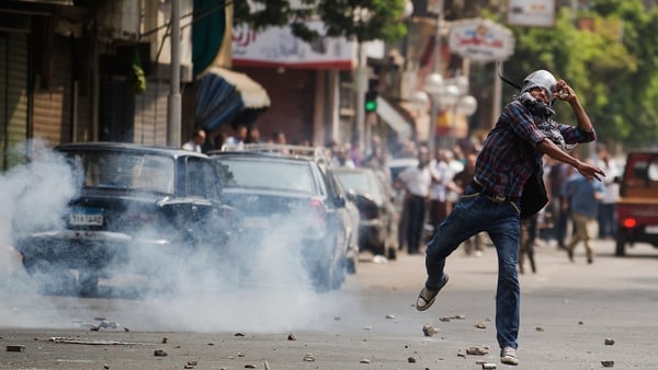 A protester throws a stone in Cairo as police fire tear gas