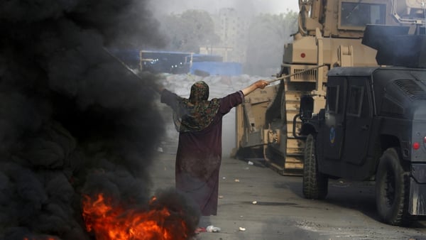 A woman tries to stop forces from entering a camp in Cairo