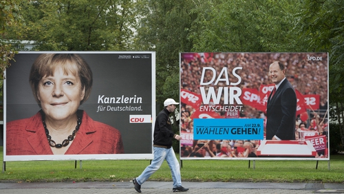 A man walks past a placard advertising CDU candidate German Chancellor Angela Merkel and SPD chancellor candidate Peer Steinbrueck in Berlin
