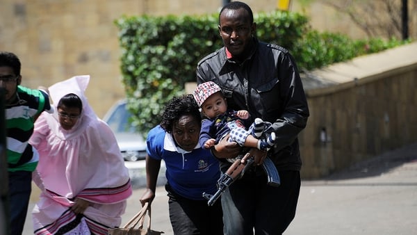 A Kenyan policeman carries a baby when helping some people to escape