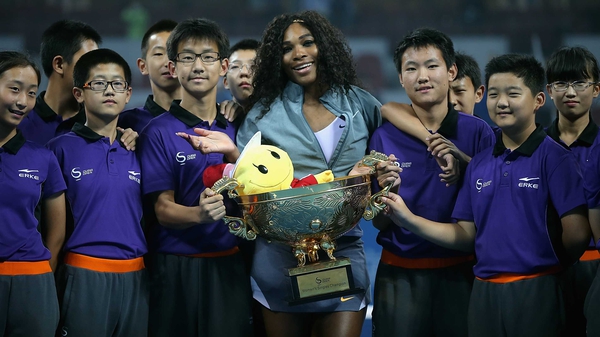 Serena Williams poses with the ball girls and boys after receiving her trophy