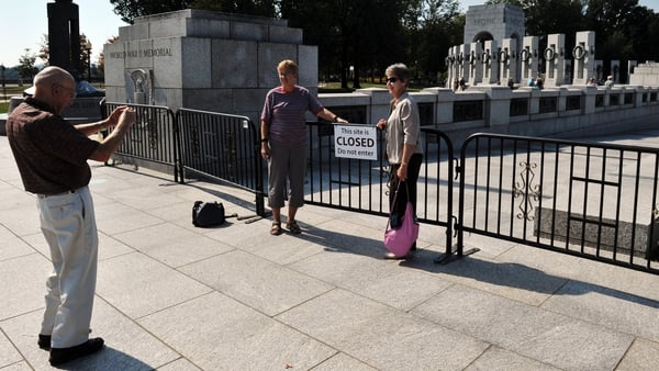 Tourists take photos behind a barricade preventing access to the World World II Memorial as the partial government shutdown continues