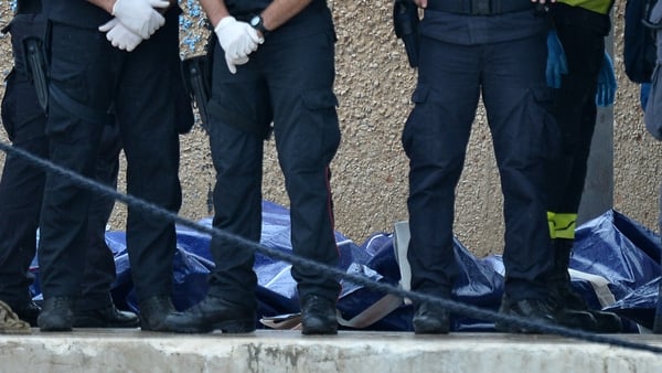 Police officers stand beside body bags containing the victims of the shipwreck in Lampedusa