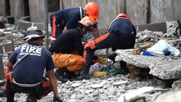 Rescuers try to uncover an unidentified man under slabs of cement in Cebu City