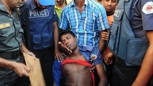 An injured Bangladeshi policeman is tended to by colleagues during clashes with garment workers in Ashulia