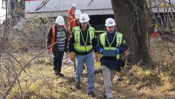 NTSB investigators carry an event recorder from the derailed commuter train in New York