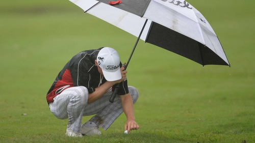 Michael Hoey attempts to remove his ball from the waterlogged turf in Durban