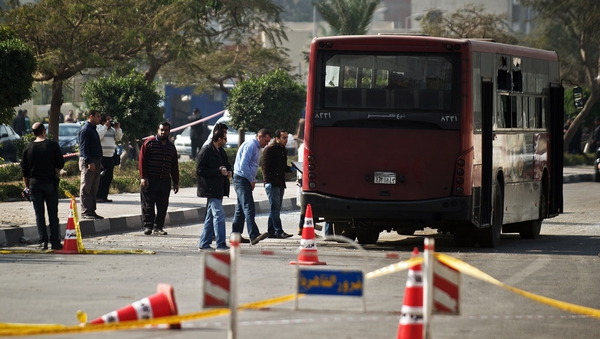 Egyptian security officials inspect the wreckage of a bus damaged by an explosion in Cairo