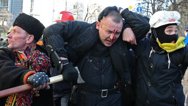 An injured policeman is escorted during the protests (EPA)