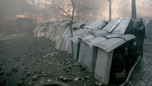 Riot policemen cover themselves with shields as they clash with protesters (EPA)