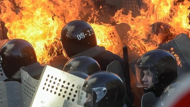 Police threw stun grenades at protesters separated from them by a line of burning tents, tyres and wood