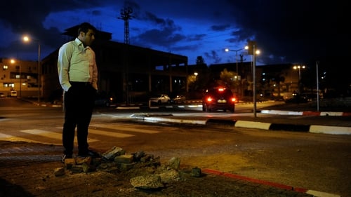An Israeli civilian stands next to a hole caused by a rocket launched from Gaza