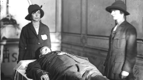 Two uniformed Cumann na mBan members stand guard over the body of Cathal Brugha in 1922. © RTÉ Photographic Archives