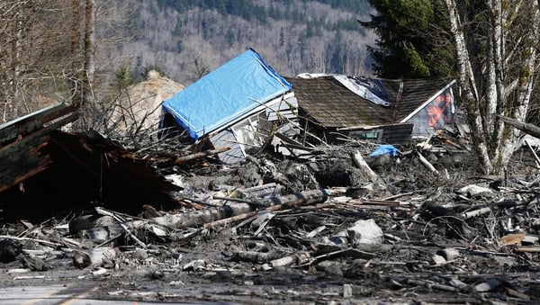 A house sits destroyed in the mud on Highway 530 next to mile marker 37