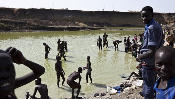 Men and children gather to bathe at a pool of water near the UN Mission in South Sudan