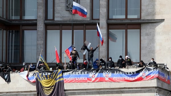 Pro-Russia activists fly Russian flags and the flag of the recently proclaimed Donetsk Republic
