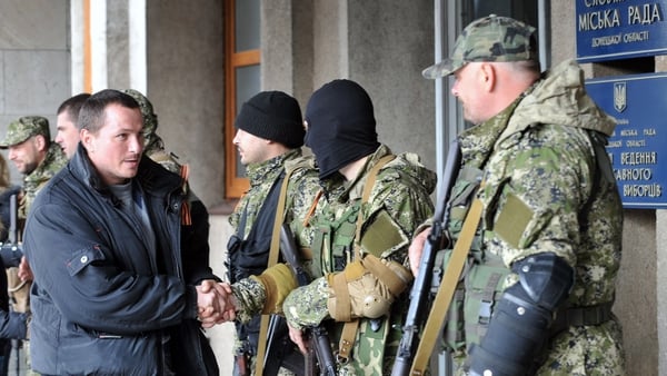 A Pro-Russia man shakes hand with armed men outside the regional administration building seized and guard by separatists in the eastern Ukrainian city of Slavyansk