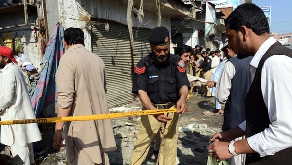 Pakistani security officials inspect the site of a bomb blast in Charsadda