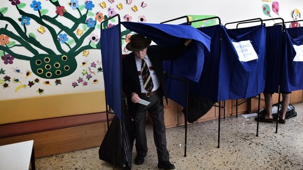 A man steps out of a polling booth after voting for the European Parliament elections at a polling station in Athens