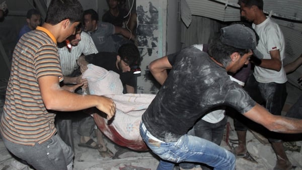 Men carry a body from a destroyed building after shelling during the night on the northern Syrian city of Aleppo