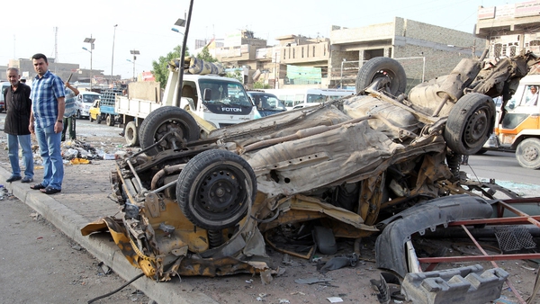Iraqis inspect destruction in the street following an explosion the previous day in Sadr City, Baghdad