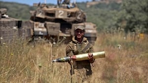 An Israeli soldier carrying a shell at a field next to tanks deployed on the Israeli-Syrian border