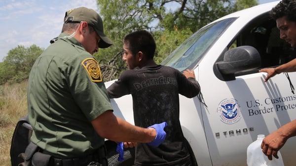 Border Patrol agents search an undocumented immigrant after taking him into custody
