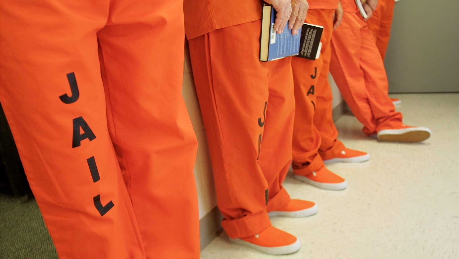 Prisoner in orange jumpsuit with chained hands on white background, back  view Stock Photo - Alamy