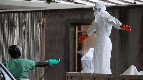 Liberian nurses are sprayed with disinfectant after preparing several bodies of victims of Ebola for burial