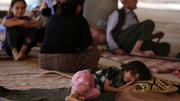 A child sleeps as Iraqi Yazidis take refuge inside a building under construction