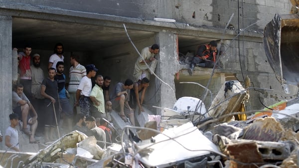 Palestinians gather around the rubble of a building destroyed following an Israeli military strike in Rafah