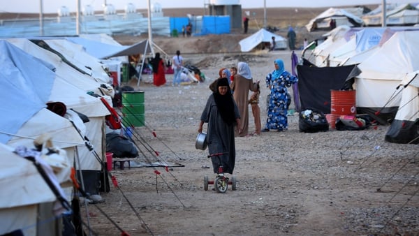 A displaced Iraqi woman walks through the Bahrka refugee camp