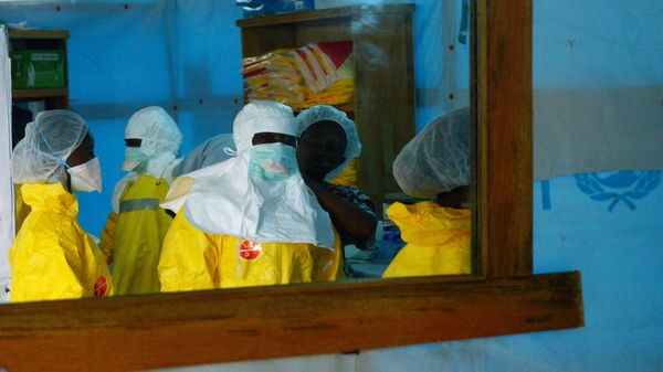 Health workers, wearing protective equipment enter a high-risk area at a hospital in Monrovia