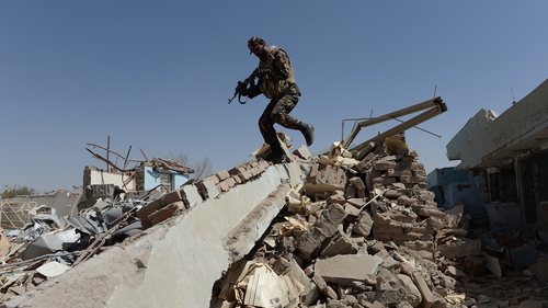An Afghan soldier walks over rubble at the scene of a suicide attack on a government compound in Ghazni