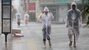 Pedestrians walk under heavy rain generated by Typhoon Vongfong in Naha city on the island of Okinawa